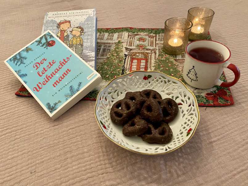 Weihnachtlicher Tisch mit Lebkuchen, Weihnachtsbüchern, Tee und Kerzen.